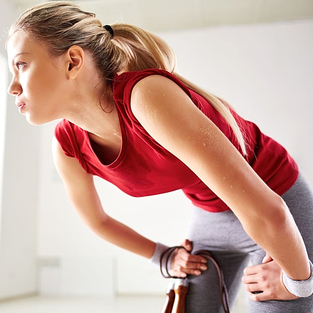 woman with hands on her knees exhaling